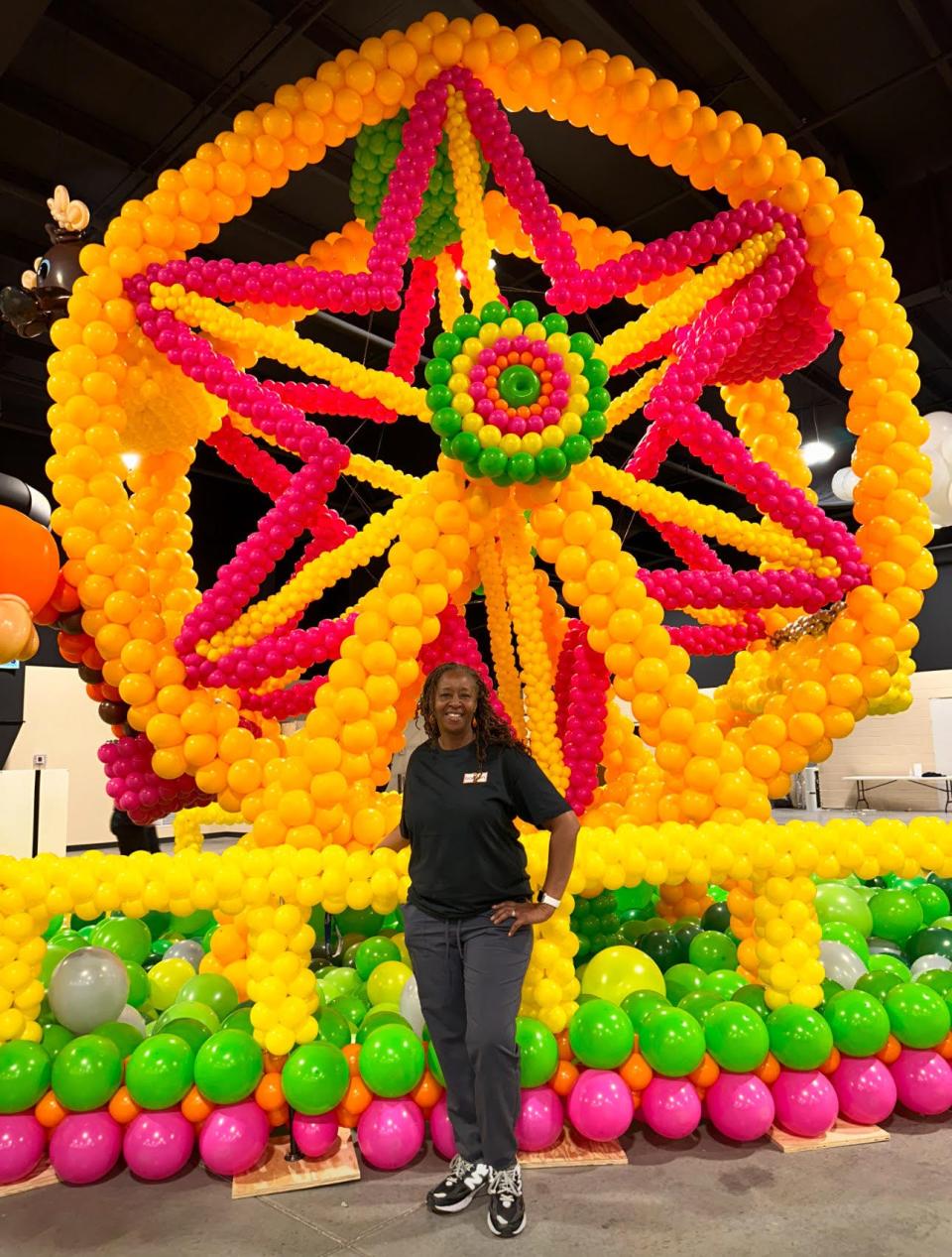 As one of 70 elite balloon artists selected to participate, Celebration Creations owner Stephanie Cofield-Mixon poses with the Ferris wheel she created in support of Ronald McDonald House at the recent "Big Balloon Build"' in Indiana in April 2024.