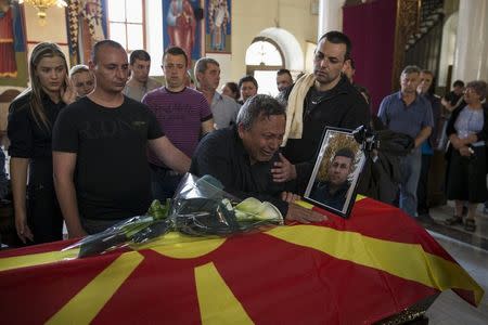 Relatives of killed policeman Sasho Samoilovski mourn next to his coffin covered in Macedonian flag inside a church in town of Tetovo, Macedonia, May 10, 2015. REUTERS/Marko Djurica