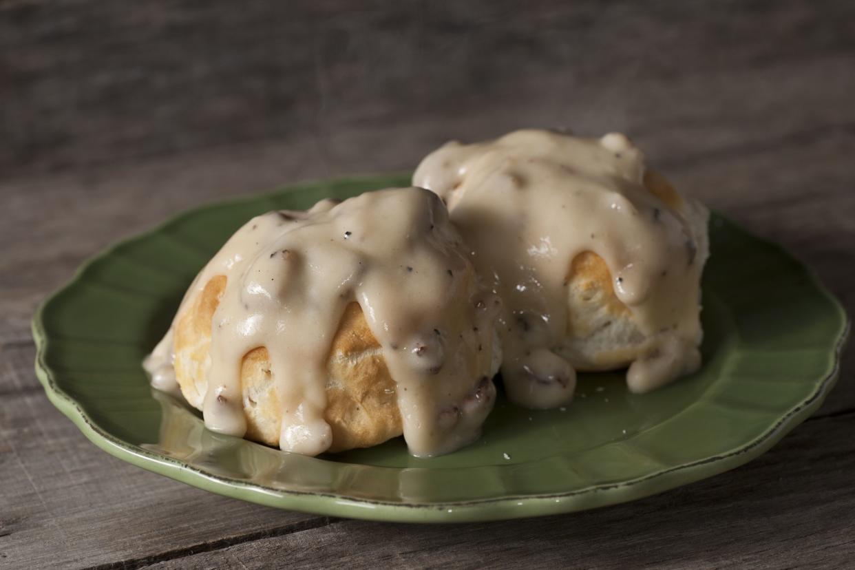 A plate full of fresh, hot, biscuits, smothered in creamy sausage gravy.