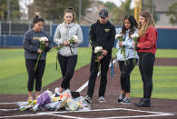 Orange Coast College students and friends of baseball coach John Altobelli lay flowers at home plate at the Orange Coast College baseball field in Costa Mesa on Sunday, Jan. 26, 2020. Coach Altobelli, his wife Keri and daughter Alyssa were killed in the helicopter crash that also killed former Lakers star Kobe Bryant. (Leonard Ortiz/The Orange County Register via AP)