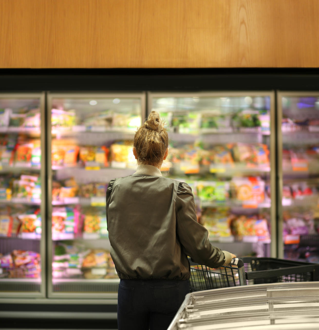 A woman looks at the frozen section in the supermarket.