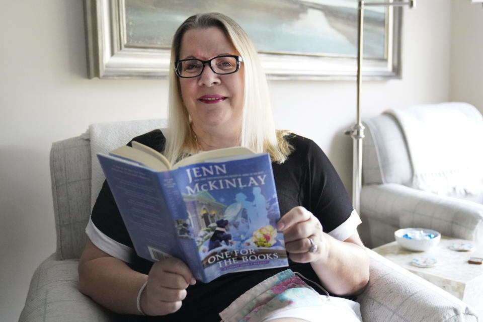 Kelly Vaiman poses for a photo in her living room where she sometimes likes to sit and read, Friday, Feb. 19, 2021, in Boynton Beach, Fla. Vaiman is an avid cozy mystery reader. (AP Photo/Wilfredo Lee)