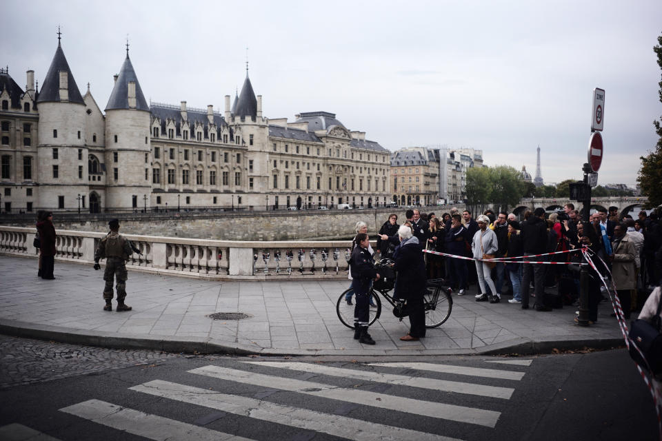 People stand behind a police tape as they are evacuated nearby the police headquarters after an incident in Paris, Thursday, Oct. 3, 2019. A French police union official says an attacker armed with a knife has killed one officer inside Paris police headquarters before he was shot and killed. (AP Photo/Kamil Zihnioglu)