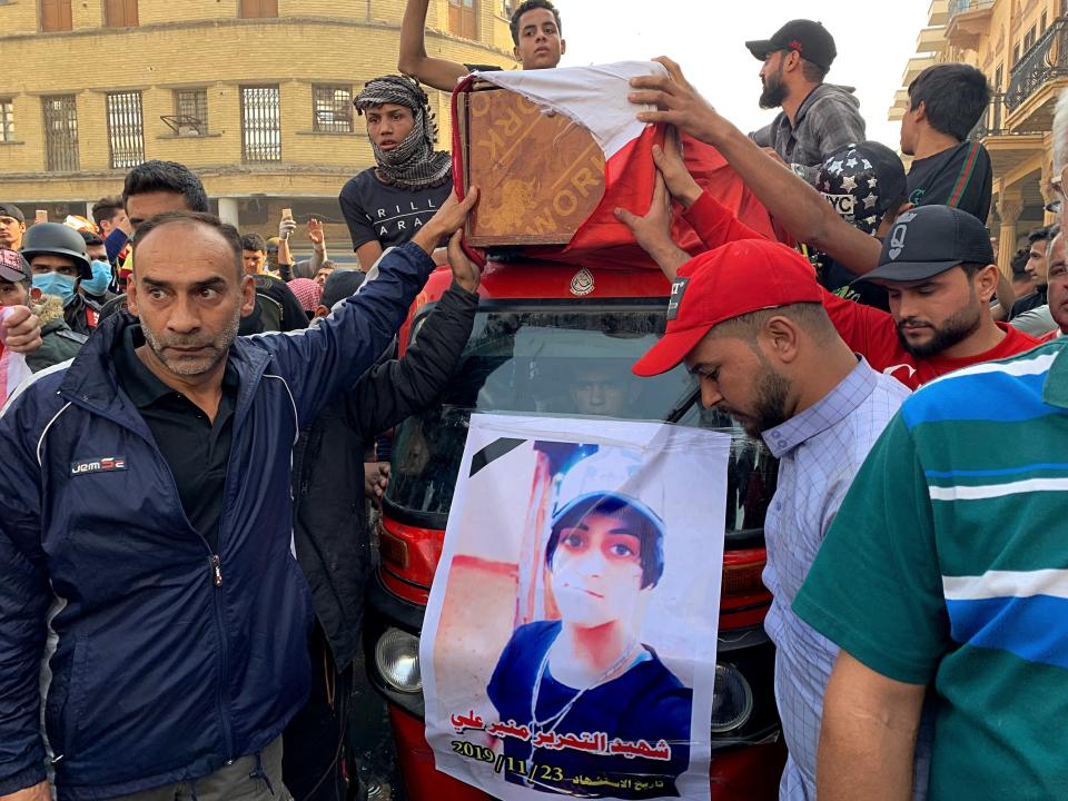 Mourners and protesters escort the flag-draped coffin of Munir Ali, seen in poster, whose family said was killed during anti-government demonstrations, during his funeral in Baghdad, Iraq, Sunday, Nov. 24, 2019. (AP Photo/Ali Abdul Hassan)