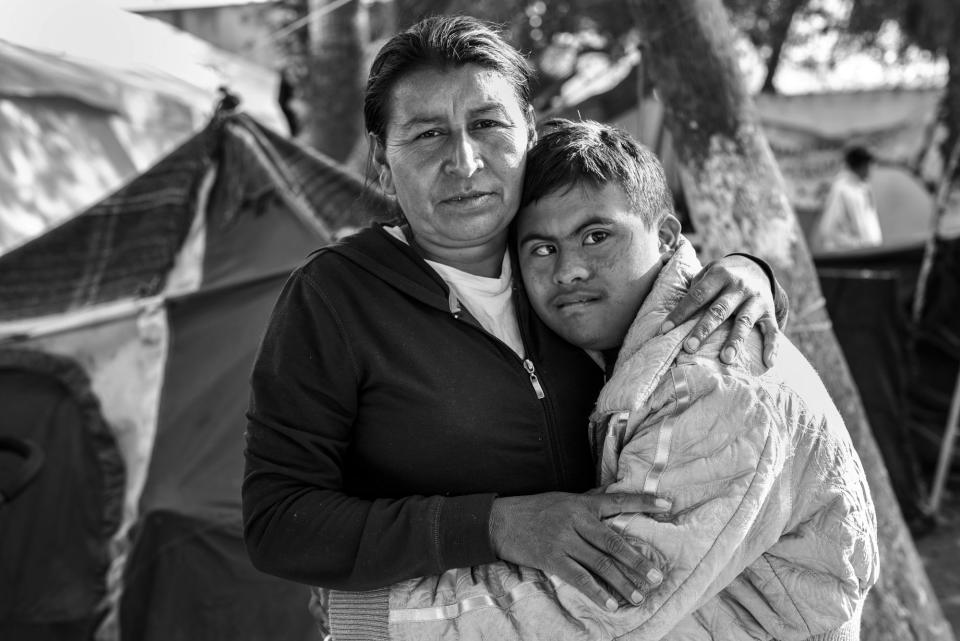 <i>A Mother and Her Son in Tijuana</i><br />Javi, who has Down syndrome, hugs his mother Maria Lucia Cardinas in the Benito Juraez shelter in Tijuana, Mexico. They left Honduras after Maria&rsquo;s two brothers were murdered and their house was burned down. Maria and Javi were allowed entry into the U.S. while their asylum case is under review. They received support from the Minority Humanitarian Foundation and currently reside in San Diego, California. (Photo: Ada Trillo)