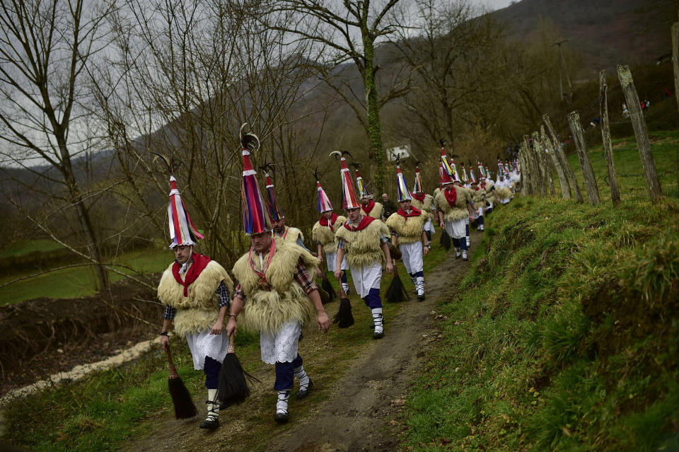 In this Monday, Jan. 27, 2020 photo, ''Joaldunak'' march along a path as they take part in a Carnival in the small Pyrenees village of Ituren, northern Spain. In one of the most ancient carnival celebrations in Europe, dozens of people don sheepskins, lace petticoats and conical caps and sling cowbells across their lower backs as they parade to herald the advent of spring. (AP Photo/Alvaro Barrientos)