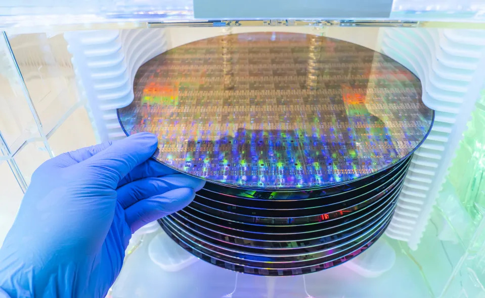 Gloved Hand Holding a Silicon Wafer in plastic holder box used in electronics for the fabrication of integrated circuits