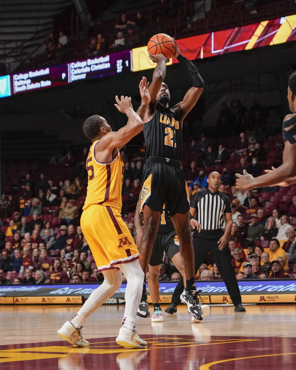 Arkansas-Pine Bluff guard Shaun Doss Jr., right, takes a shot over Minnesota guard Ta'Lon Cooper during the second half of an NCAA college basketball game on Wednesday, Dec. 14, 2022, in Minneapolis. Minnesota won 72-56.(AP Photo/Craig Lassig)