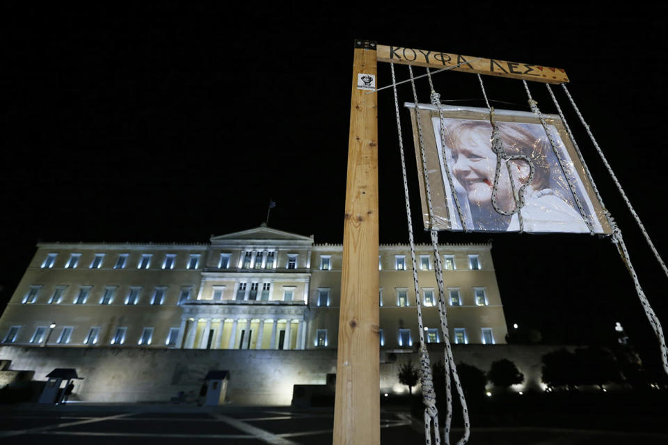 A picture of German Chancellor Angela Merkel symbolically hangs from a gibbet in front of the Parliament. The writing on the noose reads in Greek: 'Rascals'.