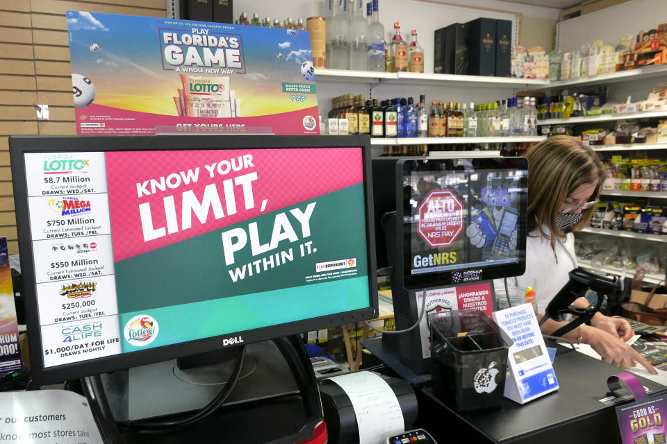 A clerk takes an order for lottery tickets next to a sign reminding customers to play responsibly, Wednesday, Jan. 13, 2021, in Orlando, Fla. Lottery players will have a shot Friday night at the fifth-largest jackpot in U.S. history after no tickets matched all the numbers in the latest Mega Millions drawing. (AP Photo/John Raoux)