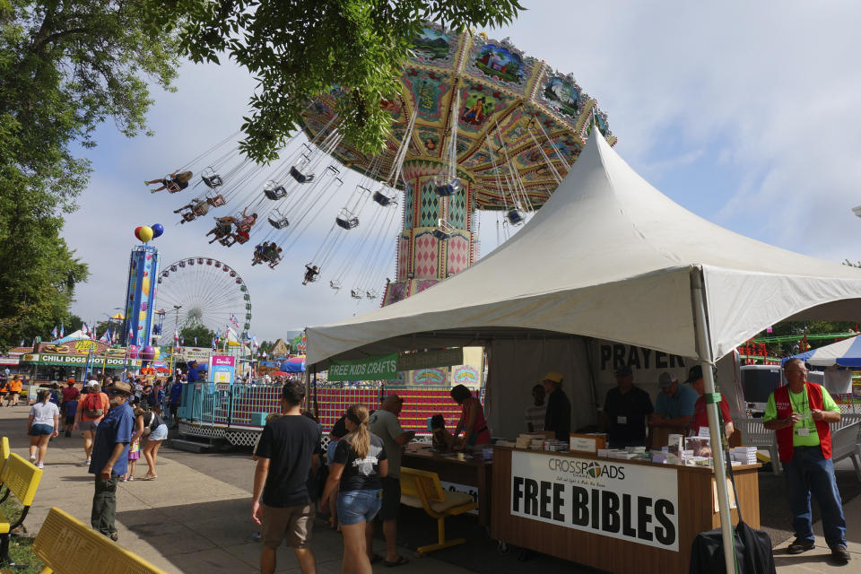 Dean Wiberg, right, volunteers at the evangelical Crossroads Chapel tent, which distributes thousands of free Bibles during the Minnesota State Fair in Falcon Heights, Minn., on Thursday, Aug. 24, 2023. For many faith communities, the fair has long been an opportunity to reach a diverse crowd that can top two million. (AP Photo/Giovanna Dell'Orto)