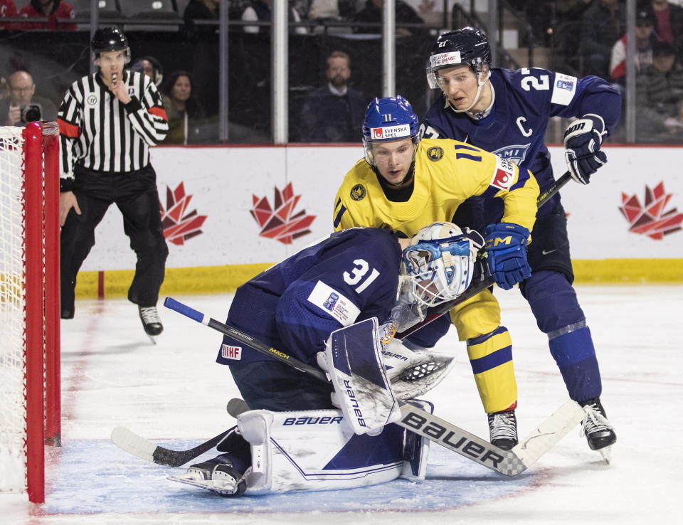 Finland goaltender Jani Lampinen smothers the puck as Sweden's Fabian Wagner looks for a rebound and Finland's Oliver Kapanen defends during the third period of a quarterfinal hockey match at the world junior championship in Moncton, New Brunswick, Monday, Jan. 2, 2023. (Ron Ward/The Canadian Press via AP)