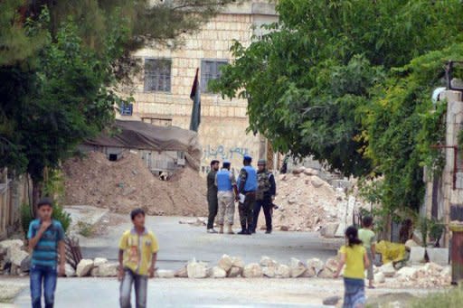 An image released by the Syrian opposition's Shaam News Network shows Syrian children walking by as UN monitors speak to Syrian government soldiers as they visit the town of Kfra Nubul. Russia condemned as counterproductive a harsher diplomatic tone against the Syrian government on Wednesday, as the opposition accused Moscow of encouraging "savage crimes" in the country