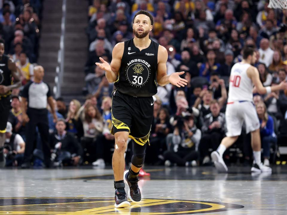 Stephen Curry runs down court and shrugs during a game.