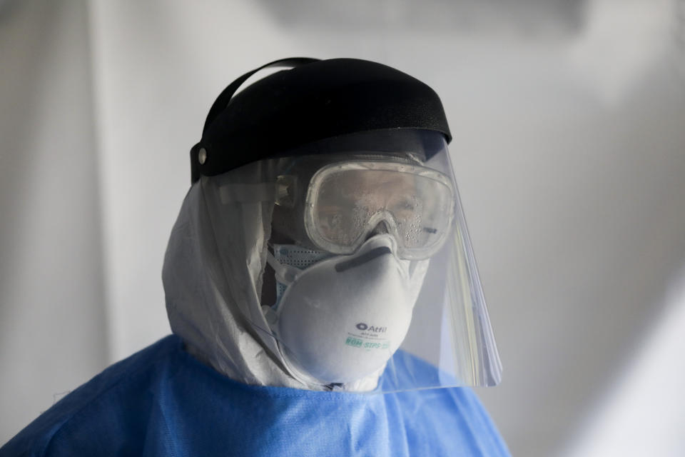 A healthcare worker, dressed in full protective gear, waits to test a person for the new coronavirus inside a mobile diagnostic tent, in the Coyoacan district of Mexico City, Friday, Nov. 13, 2020. Mexico City announced Friday it will order bars closed for two weeks after the number of people hospitalized for COVID-19 rose to levels not seen since August. (AP Photo/Eduardo Verdugo)