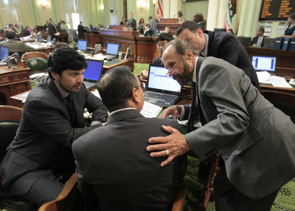 Assemblyman Jerry Hill, D-San Mateo, right, and Sen. Kevin DeLeon, D-Los Angeles, left, try to persuade Assemblyman Tony Mendoza, D-Aretesia, to vote for measure AB1500, at the Capitol in Sacramento, Calif., Monday, Aug. 13, 2012. The measure eliminates a $1 billion tax break for out-of-state corporations and uses the money for college scholarships for families earning between $80,000-$100,000, was approved 54-25 and sent to the Senate. Mendoza did not vote for the bill on first vote, but changed and provided the last vote needed for passage. (AP Photo/Rich Pedroncelli)