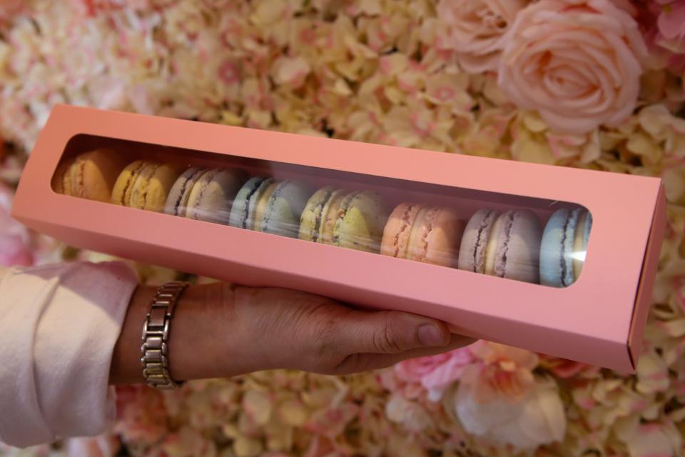 Kenedy Moore, an employee at Bien Mérité, holds a box full of macarons at the local French bakery Friday, Aug. 25, 2023. The flavors include strawberry, honey almond, lavender, blueberry, pistachio, vanilla and chocolate.