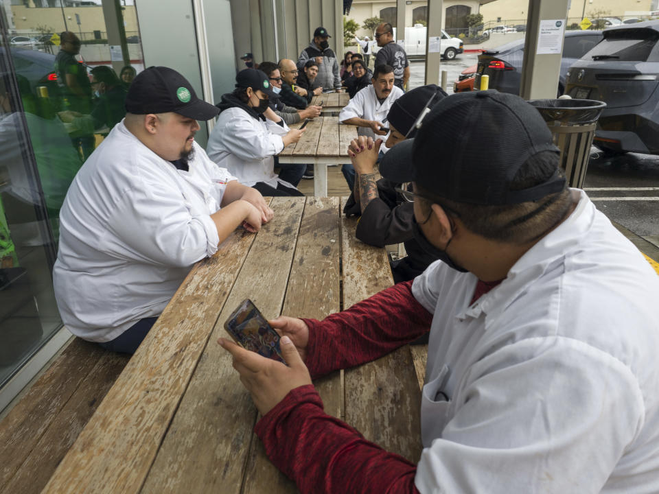 Empleados de Whole Foods Market permanecen afuera de su establecimiento debido a una interrupción en el suministro de electricidad en el sector de Silver Lake, el miércoles 15 de marzo de 2023, en Los Ángeles, California. (AP Foto/Damian Dovarganes)