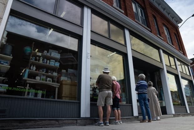 A small group of people linger outside of the Ma Cuisine store, and peer inside. The Ottawa business is closing after operating for 25 years. (Olivier Plante/CBC - image credit)