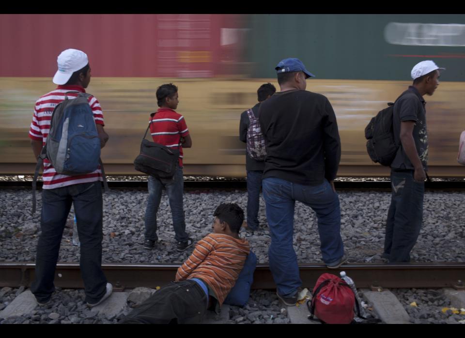 In this May 17, 2012 photo, migrants, mostly from Honduras, watch a southbound train pass by as they wait for one going north, in Lecheria, on the outskirts of Mexico City. While the number of Mexicans heading to the U.S. has dropped dramatically, a surge of Central American migrants is making the 1,000-mile northbound journey this year, fueled in large part by the rising violence brought by the spread of Mexican drug cartels. (AP Photo/Alexandre Meneghini)