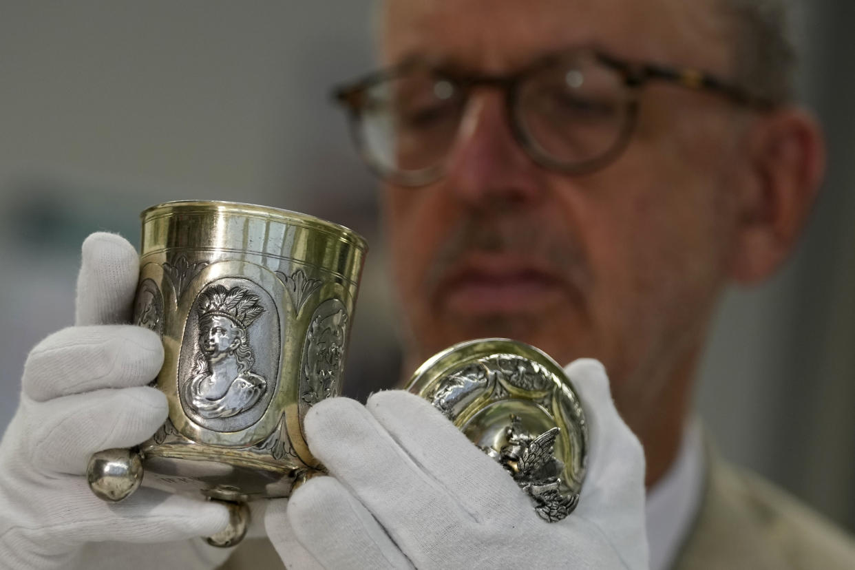 Matthias Weniger, curator of the Bavarian National Museum, lifts one of the 111 silver objects stolen by the Nazis from the Jews during the Third Reich, in Munich, Germany, Saturday, June 10, 2023. (AP Photo/Matthias Schrader)