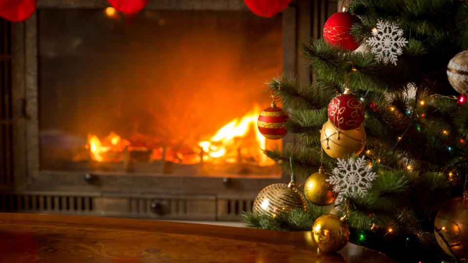 A Christmas tree with a fireplace in the background