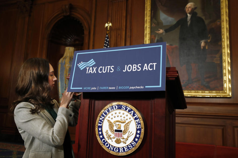 A House staff member affixes a sign that says “Tax Cuts and Jobs Act” ahead of a gathering of House Republicans making statements to the media following a vote on the GOP tax overhaul bill, Thursday, Nov. 16, 2017, on Capitol Hill in Washington. (AP Photo/Jacquelyn Martin)