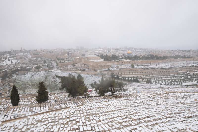 2021年2月，中東下起罕見大雪。雪花覆蓋了以色列橄欖山的墓園，遠方可見阿克薩清真寺圓頂。（AP）