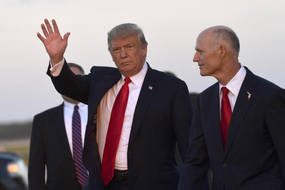 President Donald Trump, left, waves as he walks with Florida Gov. Rick Scott, right, after arriving on Air Force One at Southwest Florida International Airport in Fort Myers, Fla., Wednesday, Oct. 31, 2018. Trump is campaigning for Scott, who is challenging incumbent Democratic Sen. Bill Nelson for a seat in the Senate. (AP Photo/Susan Walsh)