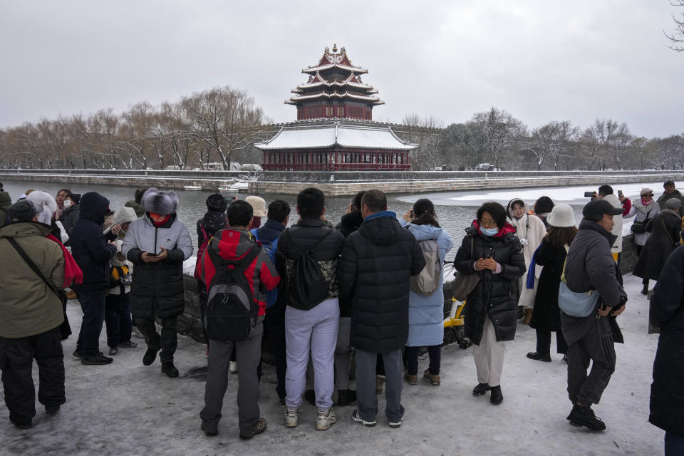 People gather to take picture of the Turret of the Forbidden City after a snow fall in Beijing, Monday, Dec. 11, 2023. An overnight snowfall across much of northern China prompted road closures and the suspension of classes and train service on Monday.(AP Photo/Andy Wong)