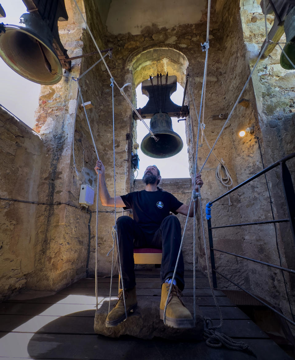 +++ON HOLD++++ Sitting in a chair with ropes looped around both feet and hands, Joan Carles Osuna, a student of the Vall d'en Bas School of Bell Ringers, performs playing all four bronze bells at the church bell tower of the12th-century Sant Romà church, at the village of Joanetes, about two hours north of Barcelona, Spain, Saturday, July 29, 2024. A school set up to revive the manual ringing of church bells has graduated its first class of 18 students after learning their ringing skills. (AP Photo/Emilio Morenatti)