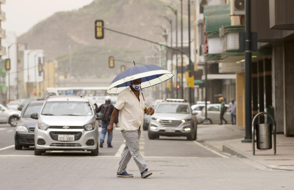 Un hombre usa una sombrilla para cubrirse de la ceniza del volcán Sangay en Guayaquil, Ecuador, el domingo 20 de septiembre de 2020. (AP Foto/Angel Dejesus)