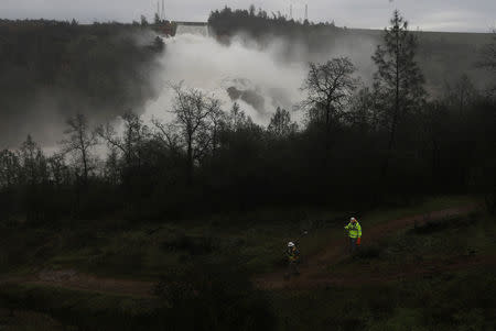 A survey crew walks near the base of the Lake Oroville Dam after an evacuation order was lifted for communities downstream in Oroville, California, U.S. February 15, 2017. REUTERS/Jim Urquhart