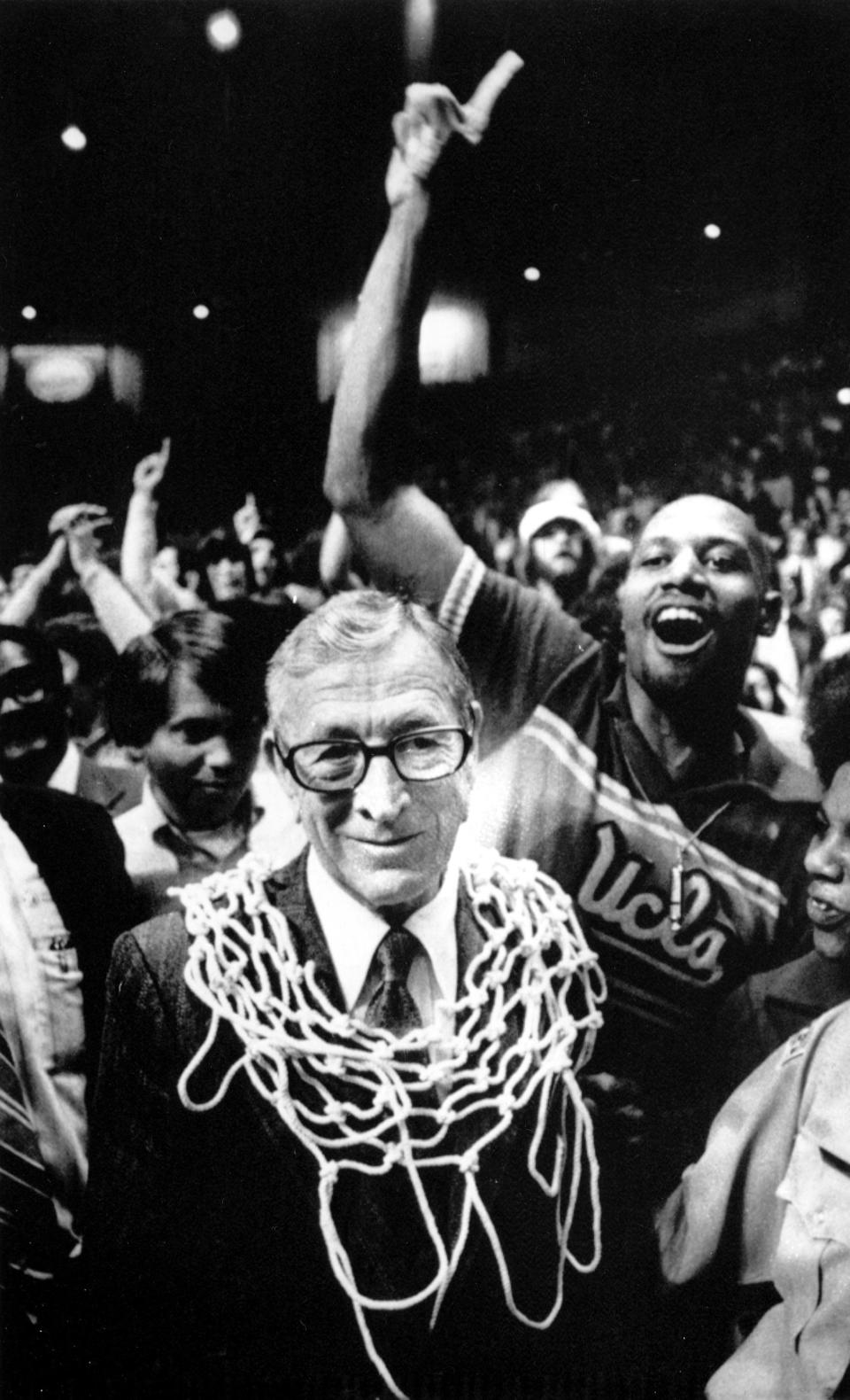 FILE - UCLA basketball coach John Wooden wears a basketball net around his neck after his team won the NCAA basketball championship over Kentucky, 92-85, in San Diego, Calif., March 31, 1975. The win gave him his tenth NCAA championship. (AP Photo, File)