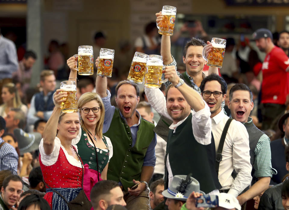 Visitors lift glasses of beer during the opening of the 186th 'Oktoberfest' beer festival in Munich, Germany, Saturday, Sept. 21, 2019. (AP Photo/Matthias Schrader)