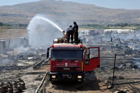 Civil defence members put out fire at a camp for Syrian refugees near the town of Qab Elias, in Lebanon's Bekaa Valley, July 2, 2017. REUTERS/Hassan Abdallah