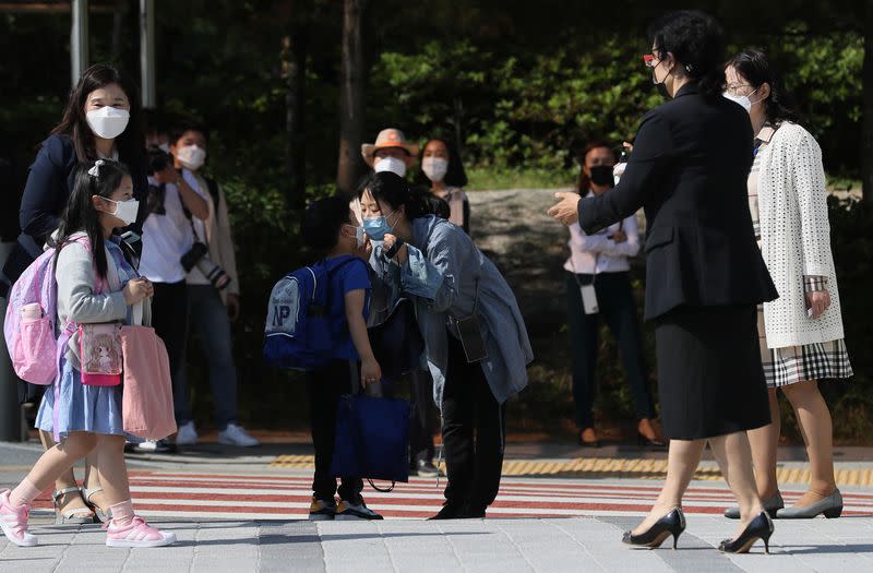 A mother kisses her child as they wear protective masks to avoid the spread of the coronavirus disease (COVID-19) at an elementary school in Seoul