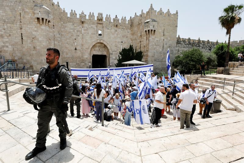 Foto del domingo de un agente de seguridad junto a un grupo de israelíes manifestando cerca de la entrada a la Ciudad Vieja de Jerusalén