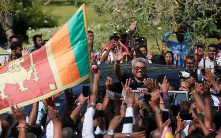 Sri Lanka's former defense secretary Rajapaksa gestures at his supporters after he returned from United States of America in Katunayake