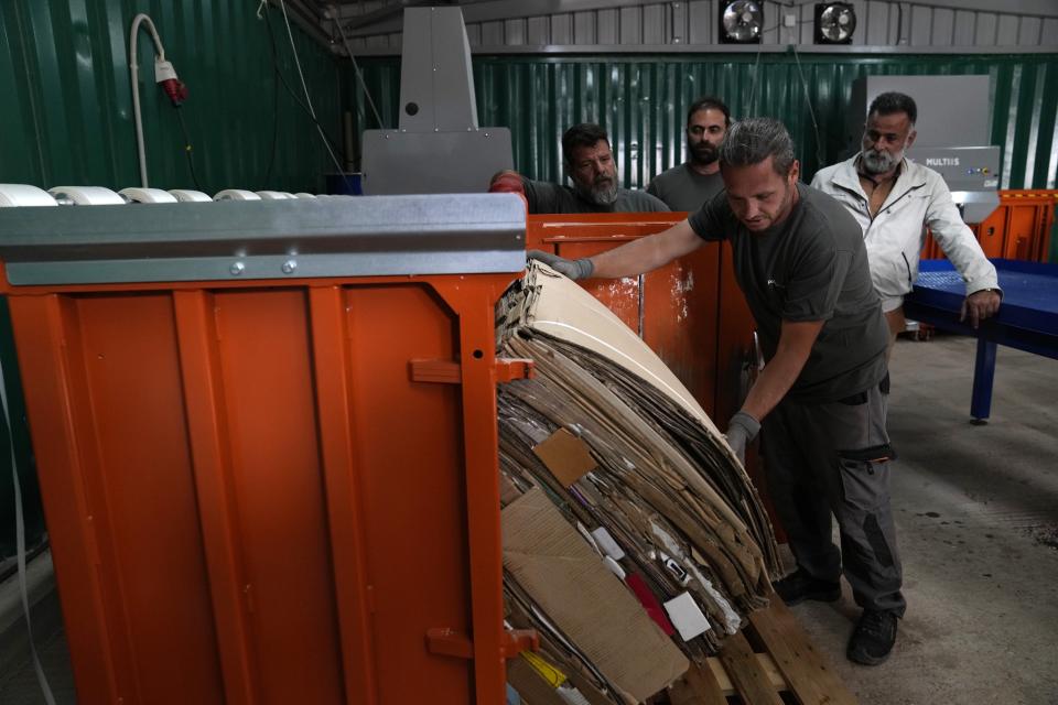 A worker takes out from a compressor cartons at a recycling plant built on old landfill site on the Aegean Sea island of Tilos, southeastern Greece, Monday, May 9, 2022. When deciding where to test green tech, Greek policymakers picked the remotest point on the map, tiny Tilos. Providing electricity and basic services, and even access by ferry is all a challenge for this island of just 500 year-round inhabitants. It's latest mission: Dealing with plastic. (AP Photo/Thanassis Stavrakis)