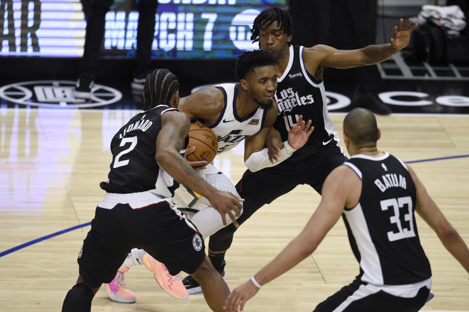 Utah Jazz guard Donovan Mitchell drives the ball between Los Angeles Clippers forward Kawhi Leonard, left, and guard Terance Mann, rear, during the second half of an NBA basketball game in Los Angeles, Friday, Feb. 19, 2021. (AP Photo/Kelvin Kuo)