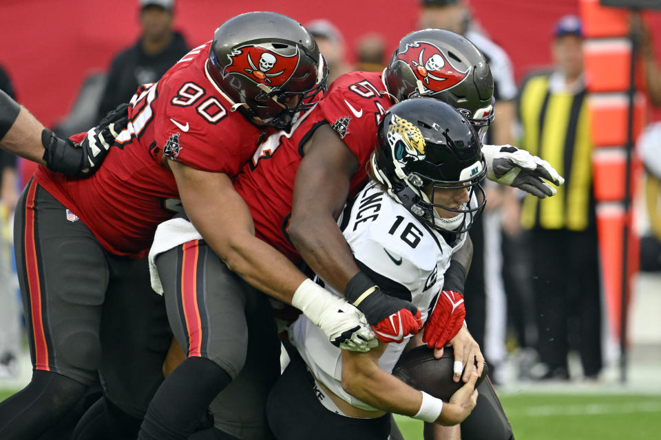 Tampa Bay Buccaneers defensive end Logan Hall (90) and linebacker Lavonte David, center, sack Jacksonville Jaguars quarterback Trevor Lawrence (16) during the first half of an NFL football game Sunday, Dec. 24, 2023, in Tampa, Fla. (AP Photo/Jason Behnken)