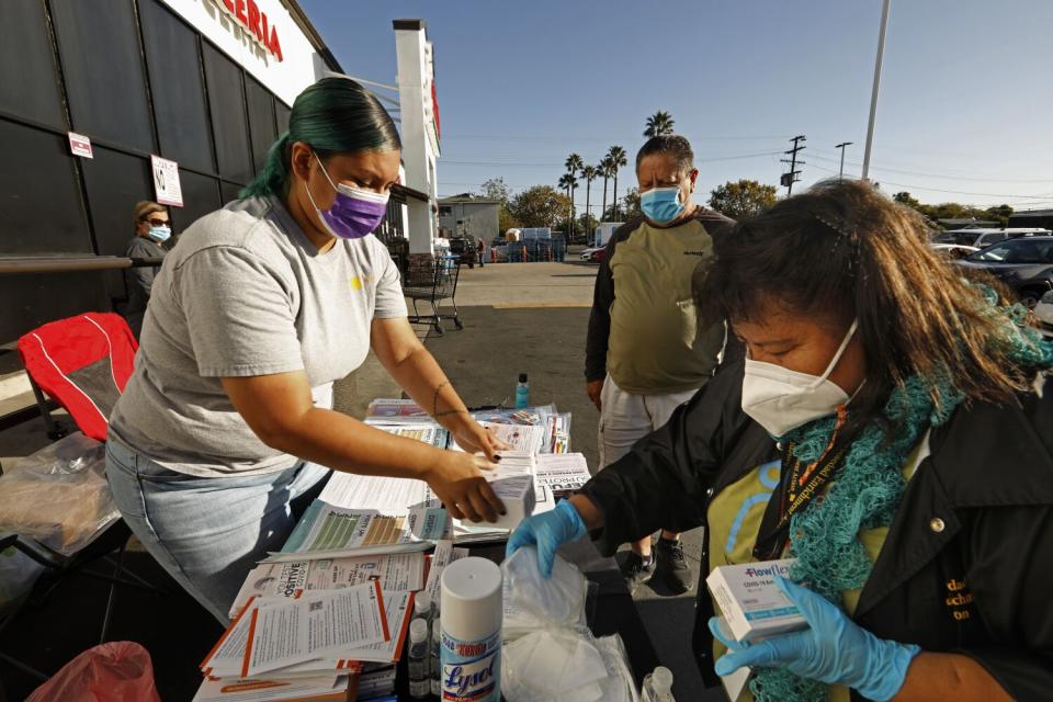 Two women work at a booth distributing COVID information.