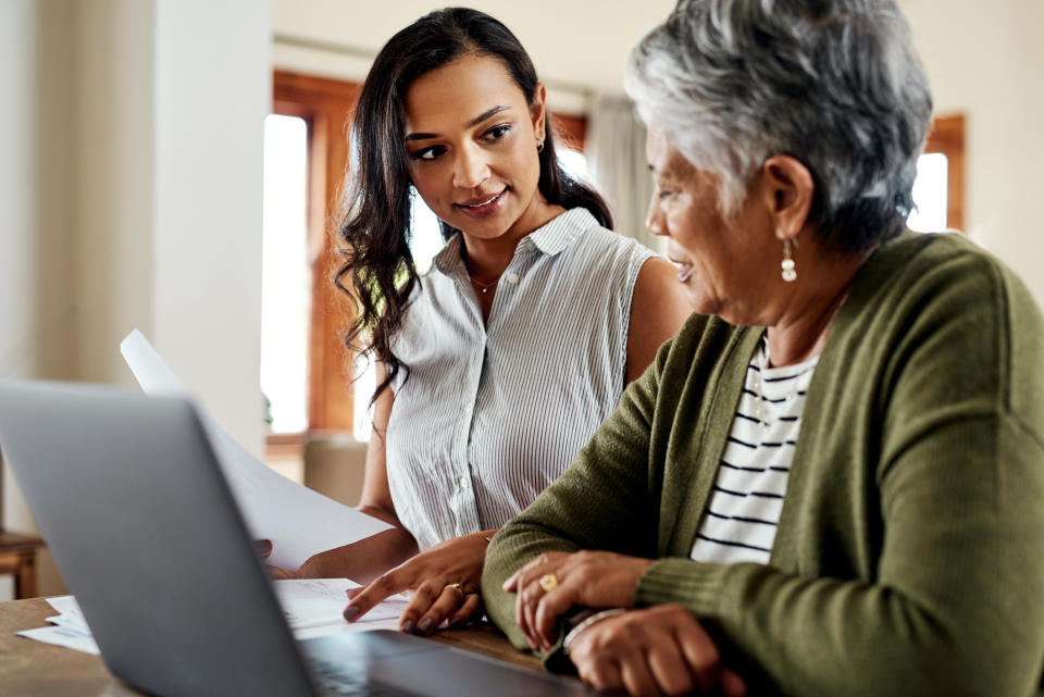 Two women, one younger and one older, are looking at a document together. The younger appears to be assisting the older