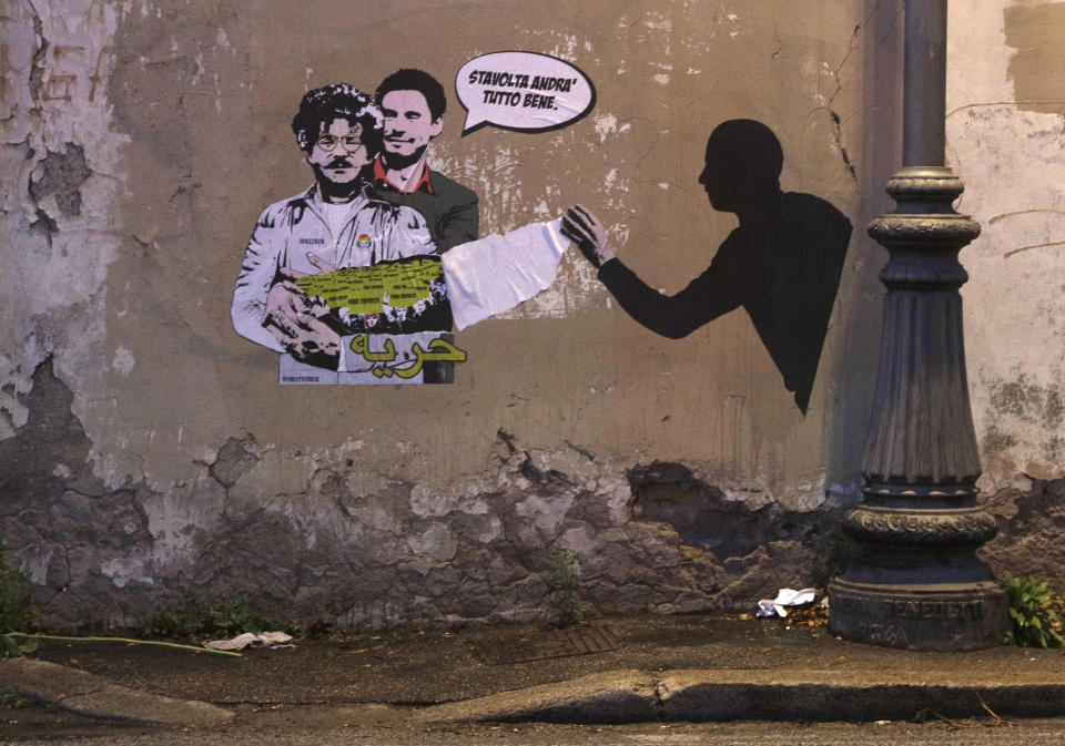 FILE - In this Feb. 19, 2020 file photo, a mural depicting detained Egyptian human rights advocate and student at the University of Bologna in Italy Patrick George Zaki, being hugged from behind by Italian researcher Giulio Regeni, who was murdered in Cairo in 2016, is displayed on a wall in Rome. The trial of Zaki who has been imprisoned for over a year in Egypt began Tuesday, Sept. 14, 2021 amid calls by human rights advocates for his immediate release, his lawyers said. Zaki appeared before a State Security Misdemeanors Court in the Delta town of Mansoura to face charges of spreading false news about Egypt domestically and abroad. Writing in Italian at top reads: "This time it will all go well", and in Arabic at the bottom reads "freedom." (AP Photo/Gregorio Borgia, File)