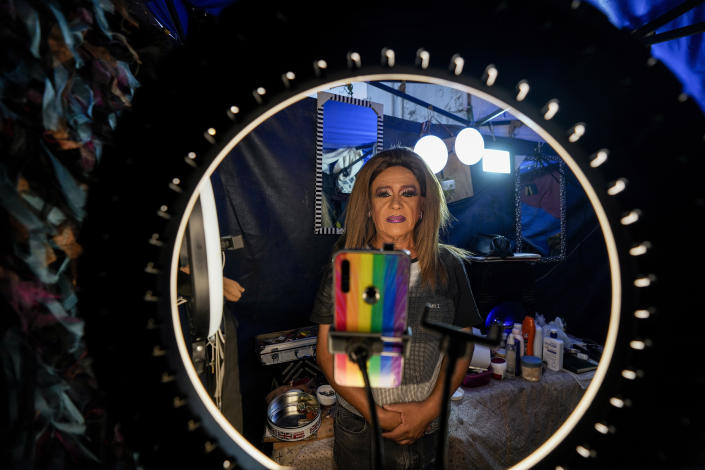 Framed by a ring light, Timoteo Circus performer Alejandro Pavés who plays the role of Alexandra Jean-Marie, records a social media video, on the outskirts of Santiago, Chile, Sunday, Dec. 18, 2022. Pavés recalled life for the Timoteo performers under the regime of Gen. Augusto Pinochet, which governed the South American country from 1973 to 1990. “It was terrible to work under the dictatorship … there was a lot of hatred for gays in Chile at that time,” Pavés told The Associated Press, recalling the number of times he had been arrested, insulted and mistreated.(AP Photo/Esteban Felix)