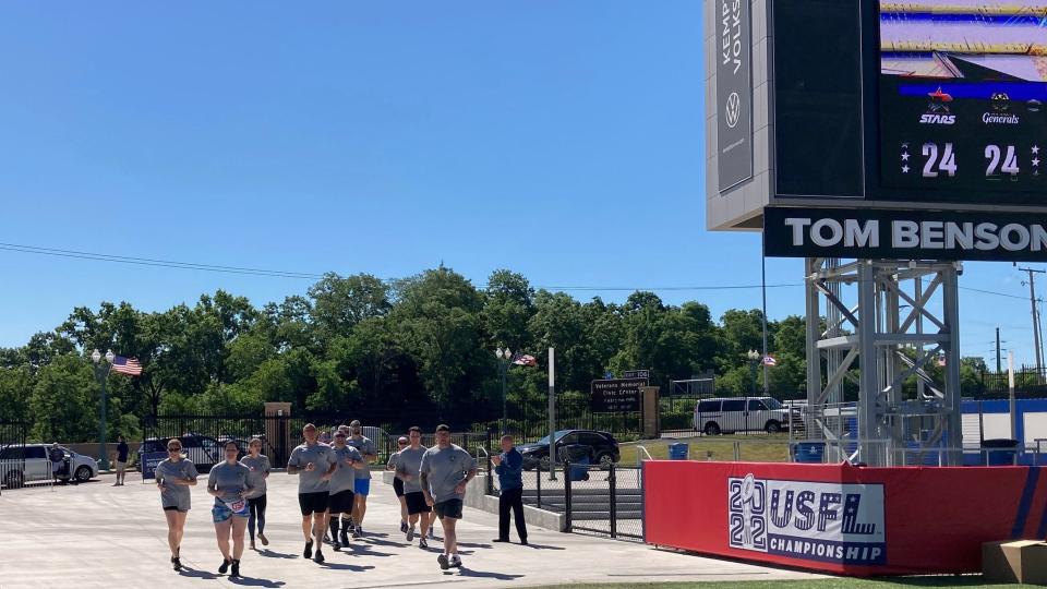 Canton police officers cross the finish line just inside of Tom Benson Stadium after a 2.25 mile run around downtown Canton and through Monument and Stadium parks.