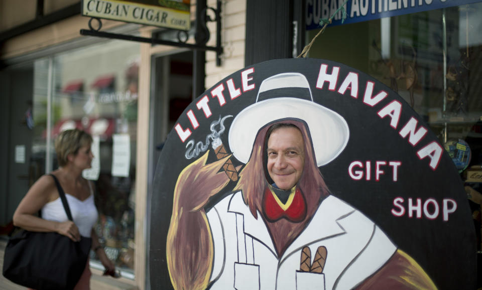 This April 30, 2014 photo shows Jorge Gonzalez, from Mexico City, standing in a cutout figure, as he tours Calle Ocho (Eighth Street) in Miami's Little Havana. Once a refuge for Cuban exiles rekindling the tastes and sounds a lost home, today Miami’s Little Havana is a mosaic of cultures and a popular tourist destination. (AP Photo/J Pat Carter)