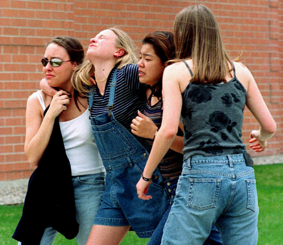 In this April 20, 1999, photo, young women head to a library near Columbine High School where students and faculty members were evacuated after two gunmen went on a shooting rampage in the school in the southwest Denver suburb of Littleton, Colo. (Kevin Higley/AP)