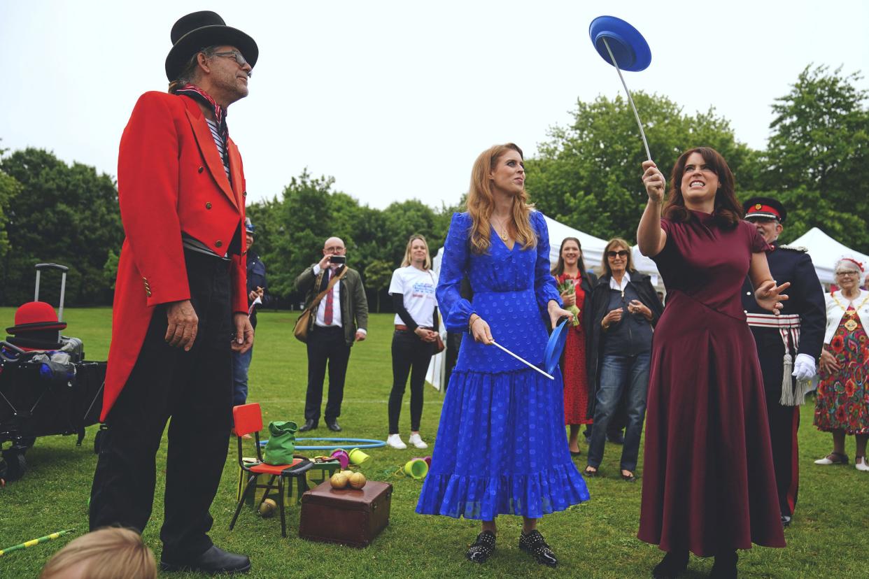 Britain's Princess Beatrice, center, and Princess Eugenie attempt to spin plates during the Big Jubilee Lunch organized by Westminster Council for local volunteer and community groups who helped during the Covid-19 pandemic, at Paddington Recreation Ground, London, Sunday, June 5, 2022, on day four of the Platinum Jubilee celebrations.